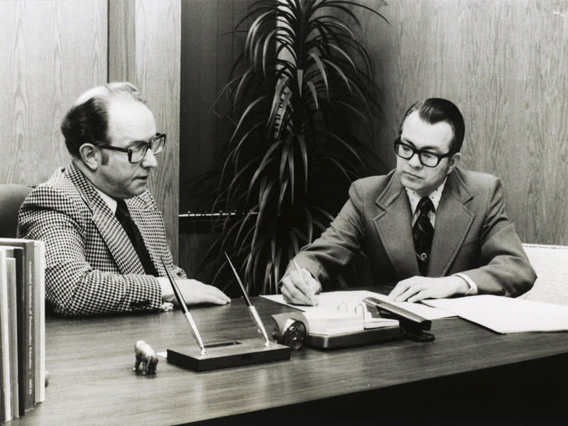 Dr. Zuck seated at a desk writing on
